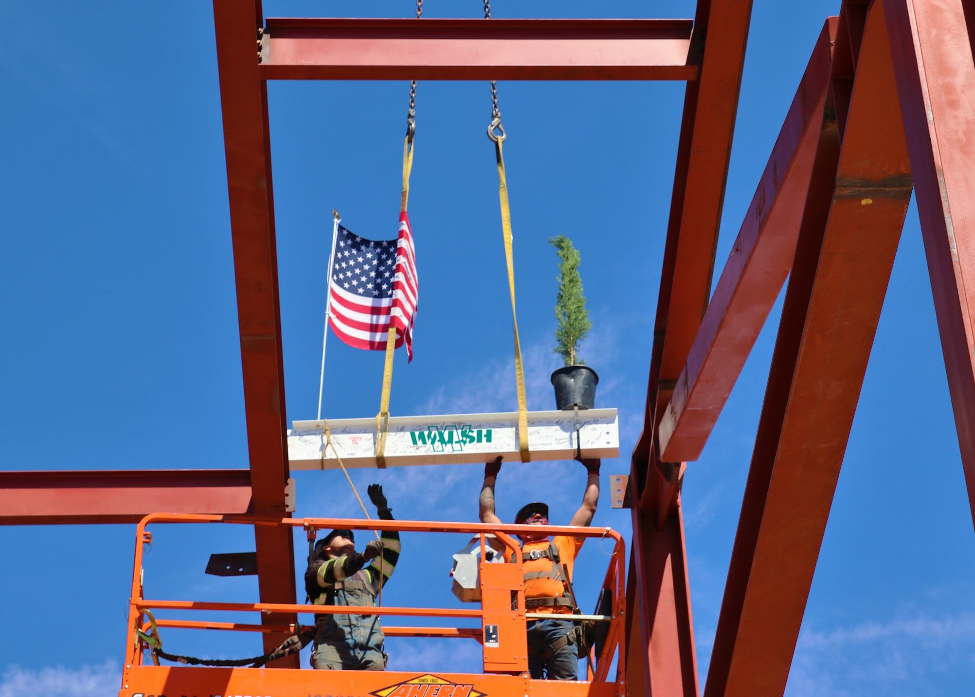 Construction crew members attach the final steel beam